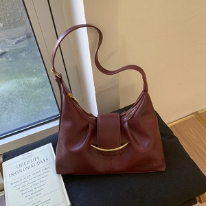 Detail of burgundy leather hobo bag with vintage sheen and curved gold metal hardware