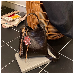Detail of dark brown faux crocodile skin texture and cute heart bear charm on a bucket bag