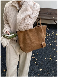 Detailed view of a brown suede tote bag with a mini pouch on a winter knit outfit