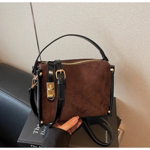 Close-up of brown suede bag featuring diamond stitching and gold metallic hardware details
