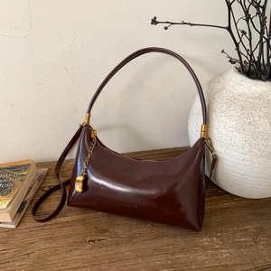 Detail of vintage dark brown leather underarm bag with gold chain on a wooden desk