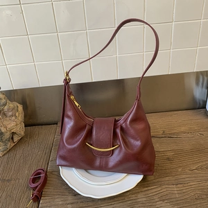 Detailed view of burgundy hobo bag with gold crescent buckle and detachable strap