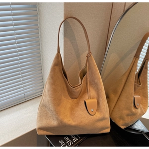 Detailed texture of a camel suede hobo bag with side pendant and natural soft lighting