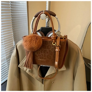 Détail du sac seau marron avec imprimé léopard, ferrures dorées et grand pompon en fourrure