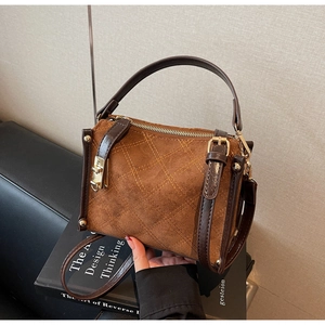 Close-up of brown suede square bag with orange quilted stitching and gold hardware details