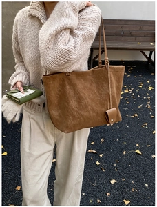 Detail of brown suede tote bag and green leather wallet in a minimalist autumn outfit