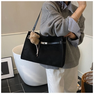 Detail of black tote bag featuring classic buckle closure and cute bear plush charm