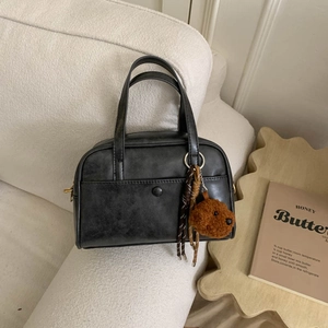 Detail of black retro textured bowling handbag with a cute brown plush bear charm