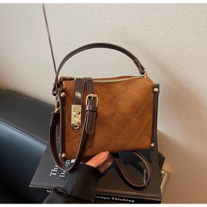 Detail of brown quilted faux suede handbag with golden turn-lock and adjustable strap