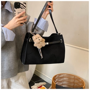 Close-up of black matte tote bag with metal lock closure and cute brown plush bear charm