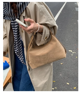Close-up of khaki suede hobo bag featuring silver adjustable buckle and wide shoulder strap