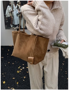 Brown suede tote bag side view with long straps and charm shown in autumn scene
