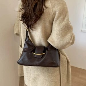 Detail of vintage brown leather shoulder bag featuring a crescent gold metal buckle detail