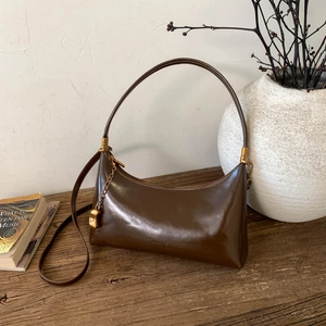 Detail view of vintage brown leather shoulder bag with gold hardware on wooden table