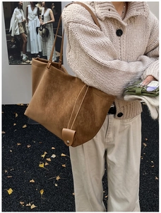 Detail of a brown suede tote bag featuring a decorative charm with a metallic snap button