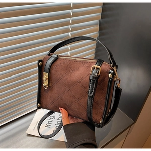 Detail of brown quilted suede handbag with black leather trim and gold hardware accents