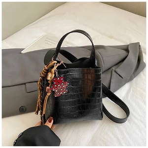 Detailed macro of black crocodile embossed bucket bag with red leopard bear charm