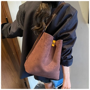 Detail of a brown suede bucket tote bag with gold twist lock and a crossbody strap