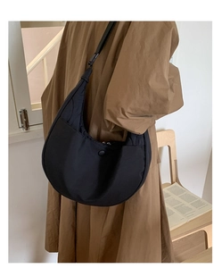 Dettaglio della borsa a mezzaluna nera in nylon minimalista portata a spalla da donna