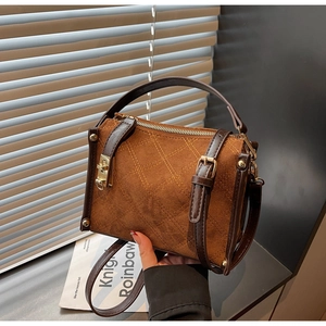Detail of vintage brown suede crossbody bag with quilted stitching and gold hardware