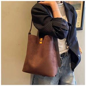 Detail of vintage brown suede bucket bag featuring a polished gold twist-lock closure