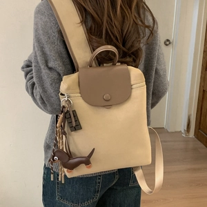 Detail of canvas backpack with leather flap, single buckle, and dachshund charm on side