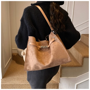 Detail of caramel suede tote bag featuring a silver twist lock and polished strap