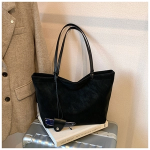 Close-up of black suede tote bag with leather glasses case on silver luggage and blazer