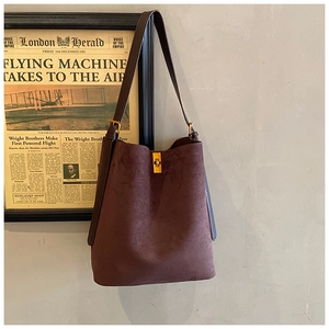 Detail view of suede bucket bag featuring vintage gold square lock and chocolate texture