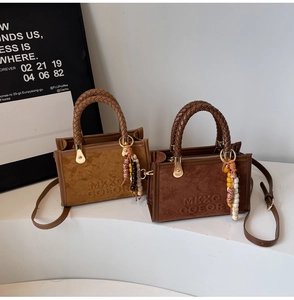 Détail du sac bandoulière rétro en daim avec poignée tissée et accessoire perlé chic