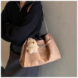 Detail of vintage brown suede tote bag with metal twist lock and plush bear charm
