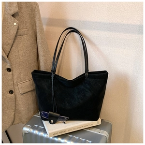 Macro detail of black suede tote bag with leather eyeglass pouch on travel suitcase