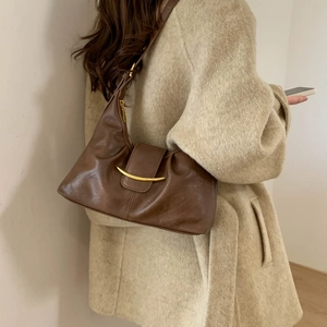 Close-up of brown leather hobo bag with gold hardware worn with a wool coat