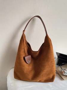 Brown suede hobo tote bag with a laptop and headphones for a stylish minimalist look