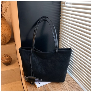 Detail of a black textured tote bag with leather straps and a side glasses case attachment
