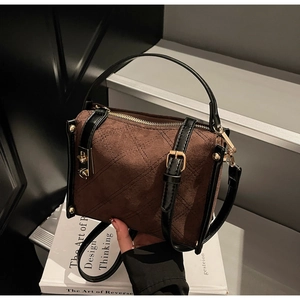 Detail of brown suede square bag featuring quilted patterns and gold hardware