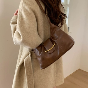 Detail of soft brown leather hobo bag with gold half-moon buckle on wool coat