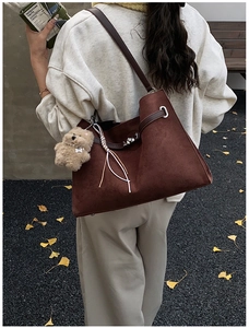 Macro detail of dark brown suede tote featuring metallic twist lock and chic bag charms