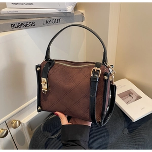 Detail of brown suede crossbody bag with quilted stitching and gold hardware accents