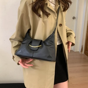 Detail of black leather trapezoid bag with gold crescent buckle on a khaki trench coat