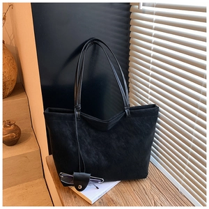 Detail of black matte suede tote bag with slim straps on wooden surface with shadows