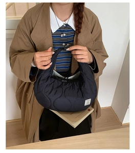 Dettaglio borsa hobo nera trapuntata con cuciture a onda ed etichetta del marchio