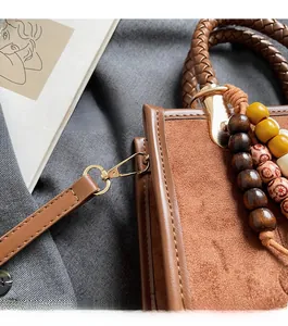 Détails du sac cabas en daim marron avec boucles dorées et breloque en perles de bois