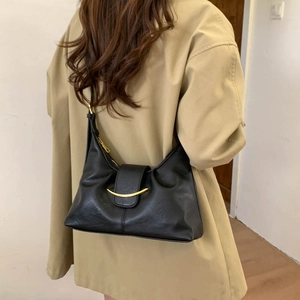 Close-up of black leather half-moon bag featuring a unique gold crescent metal buckle