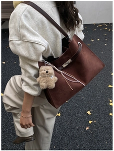 Detail of vintage matte leather tote bag with metal twist lock and cute bear charm