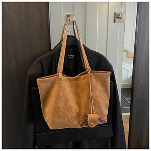 Detail view of large brown suede tote bag with matching leather glasses holder charm