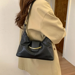 Detailed side view of black croissant bag with crescent gold buckle on female model