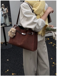 Detail of vintage brown suede tote bag with silver twist lock and cute teddy bear charm