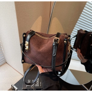 Close-up of brown suede crossbody bag with quilted diamond pattern and gold hardware