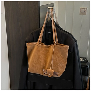 Detailed macro of brown vintage tote bag with textured matte leather and glasses case charm